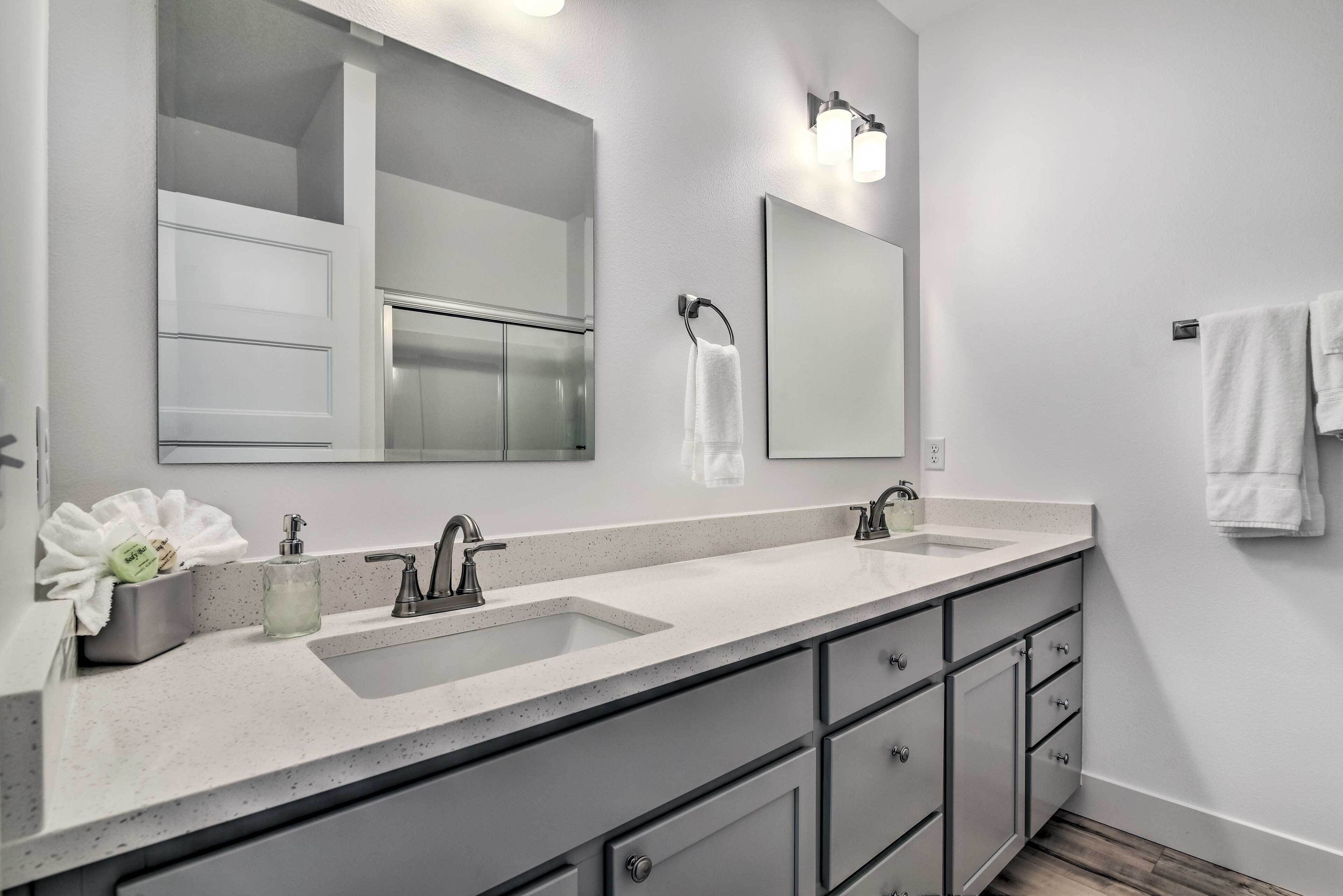 Une salle de bain moderne avec deux lavabos, un grand miroir et un porte-serviettes.