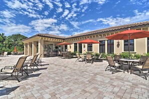 An outdoor patio area with tiled flooring, outdoor seating, and red umbrellas.