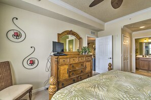 A bedroom with a large bed, a dresser, a television, and a mirror.