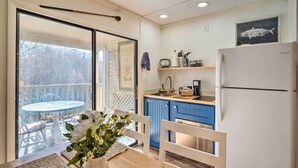 A kitchen with a white refrigerator, blue cabinets, and a dining area with a table and chairs. - Balcony + Pool Access! Couples Escape in Lake Lure (Lake Lure)