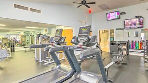 A gym with treadmills, exercise bikes, and a television displaying a sports event. - Balcony + Pool Access! Couples Escape in Lake Lure (Lake Lure)