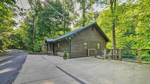 A log cabin with a green roof, surrounded by a forest.