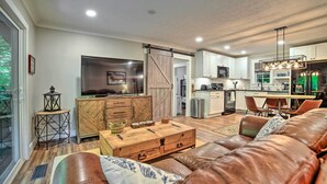 A modern living room with a leather sofa, wooden coffee table, and a sliding barn door leading to the kitchen.