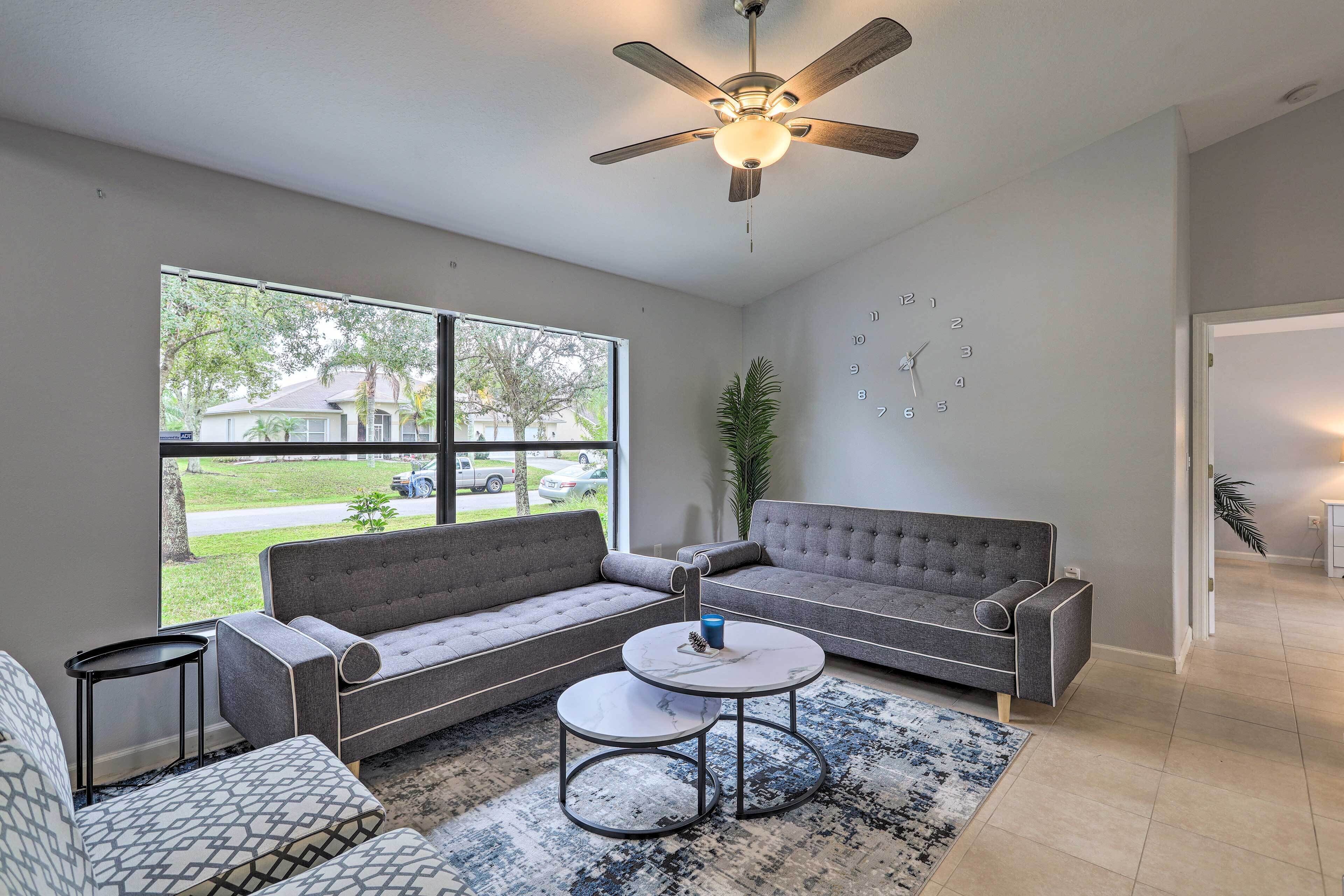 A modern living room with a grey sectional sofa, a round coffee table, and a ceiling fan.
