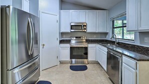A modern kitchen with stainless steel appliances, white cabinetry, and a granite countertop. - Charming Palm Bay Retreat w/ Spacious Yard! (Palm Bay)