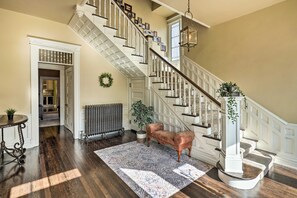 A grand staircase with white balusters and a patterned rug on the floor. - Historic Cañon City Home: Hot Tub & Fenced Yard (Canon City)