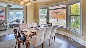 Un coin repas avec une table en bois, dressée pour quatre personnes, entourée de chaises rembourrées.