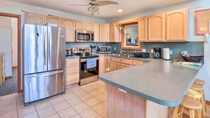 A modern kitchen with stainless steel appliances, wooden cabinets, and a large island with bar stools. - Near Hiking: Lakefront Albrightsville Home w/ Deck (Albrightsville)