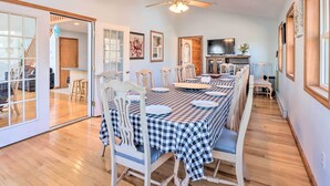 A dining area with a checkered tablecloth, white chairs, a ceiling fan, and a television on the wall. - Near Hiking: Lakefront Albrightsville Home w/ Deck (Albrightsville)