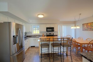 Una cocina moderna con electrodomésticos de acero inoxidable, una isla central y un comedor con sillas de madera.