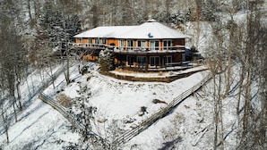 Een met sneeuw bedekte lodge met een rond ontwerp, een balkon en een besneeerd landschap.