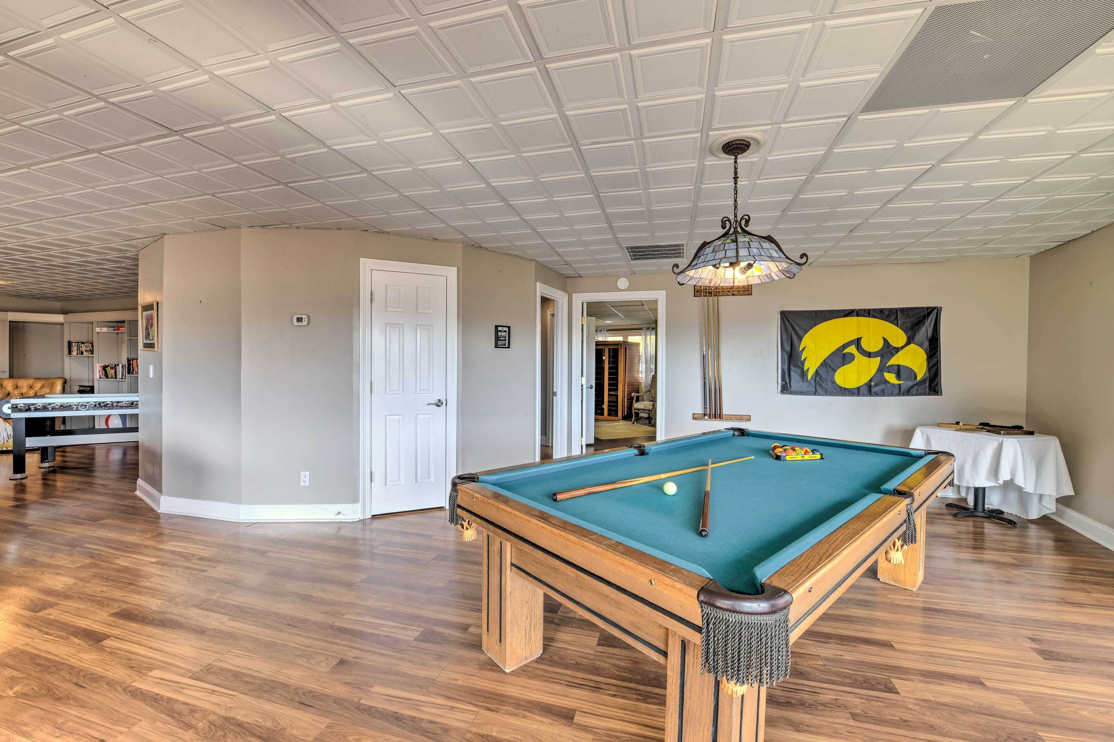 A spacious room with a pool table, wooden flooring, and a ceiling with a grid pattern.