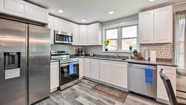 A modern kitchen with white cabinets, stainless steel appliances, a brick backsplash, and a large window with a view. - 1 Mi to Hersheypark: Family Home w/ Game Room! (Hershey)