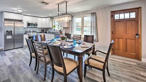 A modern kitchen with stainless steel appliances, a dining area with a wooden table and chairs, and a large window with curtains. - 1 Mi to Hersheypark: Family Home w/ Game Room! (Hershey)