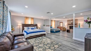 A spacious bedroom with a large bed, a leather sofa, and a separate seating area with a chair and a small table. - 1 Mi to Hersheypark: Family Home w/ Game Room! (Hershey)