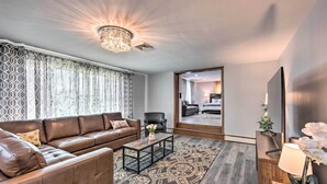 A modern living room with a brown leather sofa, a patterned rug, a wooden coffee table, and a chandelier. - 1 Mi to Hersheypark: Family Home w/ Game Room! (Hershey)