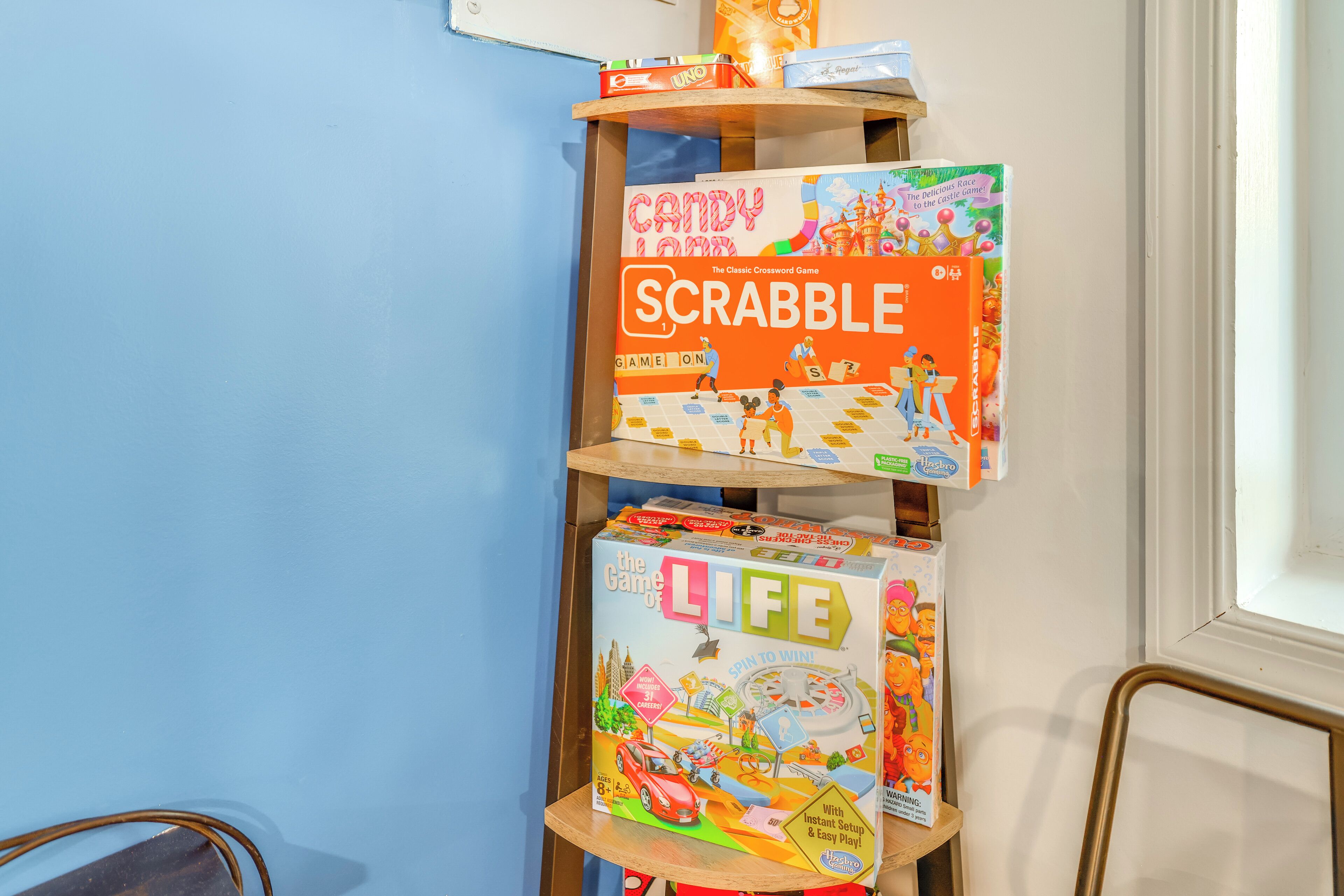 Una repisa con juegos de mesa como Candy Land, Scrabble y Life.