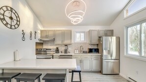 A modern kitchen with a central island, stainless steel appliances, and a large clock on the wall. - < 7 Mi to Slopes: Inviting Pocono Mtn Retreat! (Albrightsville)