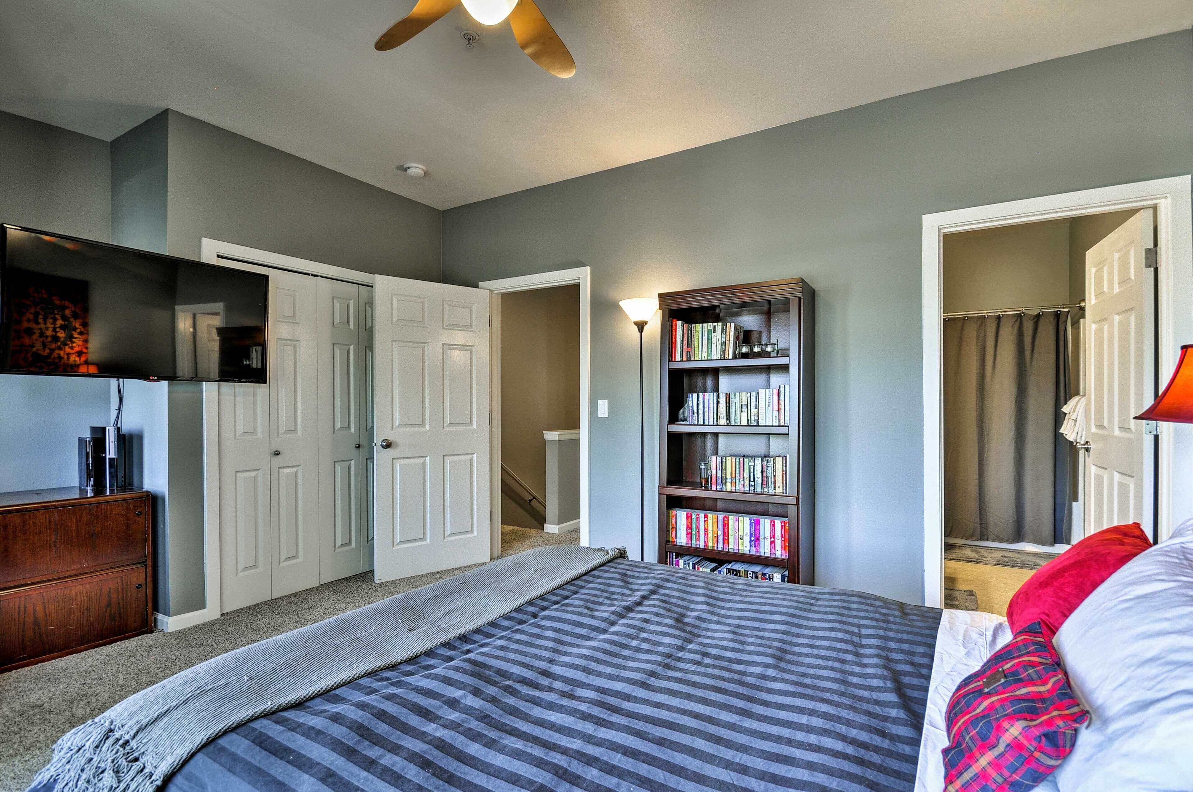 Une chambre à coucher comprenant un lit, une bibliothèque, une commode et une porte donnant sur une autre pièce.