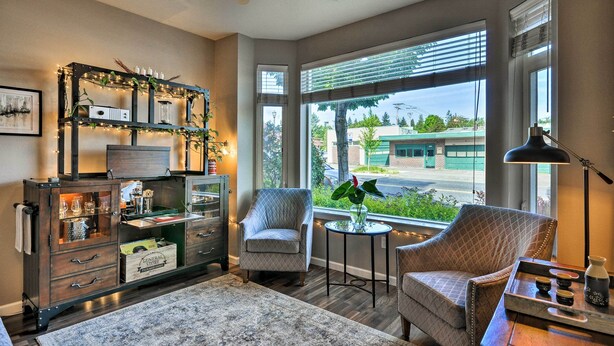 A cozy living room with a fireplace, comfortable seating, and a large window offering a view of the street. - Modern Vancouver Townhome - Right on Main St! (Vancouver)