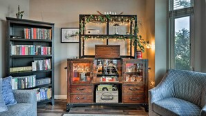 A cozy living room with a bookshelf, a wooden cabinet with glass doors, and a patterned sofa. - Modern Vancouver Townhome - Right on Main St! (Vancouver)