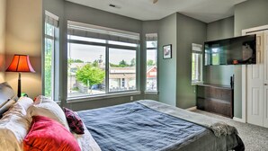 A bedroom with a bed, a desk, a lamp, a TV, and large windows. - Modern Vancouver Townhome - Right on Main St! (Vancouver)