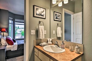 A modern bathroom with a large mirror, a sink, and a window with a view of trees and a building. - Modern Vancouver Townhome - Right on Main St! (Vancouver)