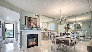 A spacious dining area with a fireplace, white furniture, and a chandelier. - Charming Ormond Beach Condo w/ Ocean Views! (Ormond Beach)