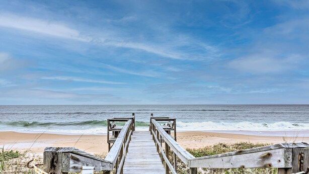 A wooden boardwalk leading to a beach with waves in the background. - Charming Ormond Beach Condo w/ Ocean Views! (Ormond Beach)