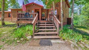 A wooden cabin with a front porch, steps leading up to the entrance, and an American flag. - Deck & Hot Tub Bear Country Cabin, Upper Canyon (Ruidoso)