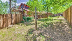 A wooden deck with a wooden fence, a wooden post, and a building with a red roof in the background. - Deck & Hot Tub Bear Country Cabin, Upper Canyon (Ruidoso)