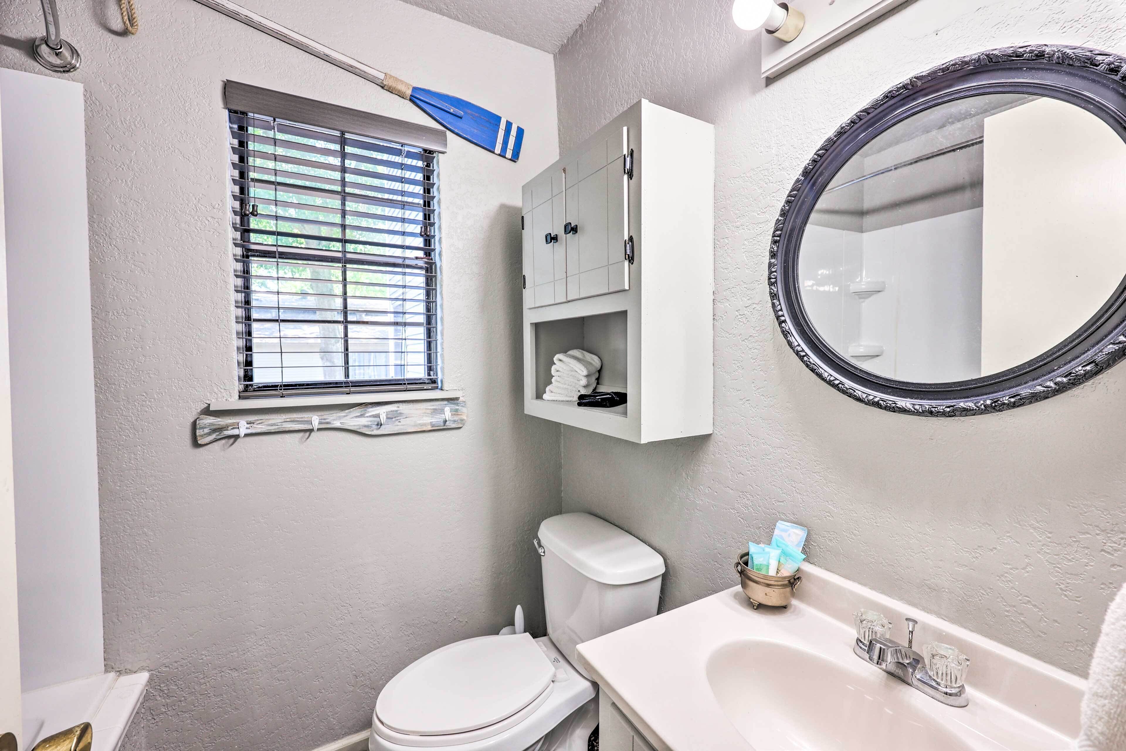 Ein Badezimmer mit Toilette, Waschbecken, Spiegel und Fenster mit Jalousien.