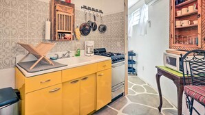 A compact kitchen with yellow cabinets, a stove, and a microwave on a table.