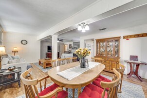 Un comedor con una mesa de madera, sillas rojas y un jarrón con girasoles.