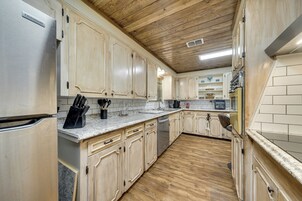 Una cocina con armarios de madera, un refrigerador de acero inoxidable, un lavavajillas y un microondas.