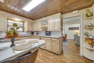 Una cocina con armarios de madera, encimera de mármol y un comedor con mesa y sillas.