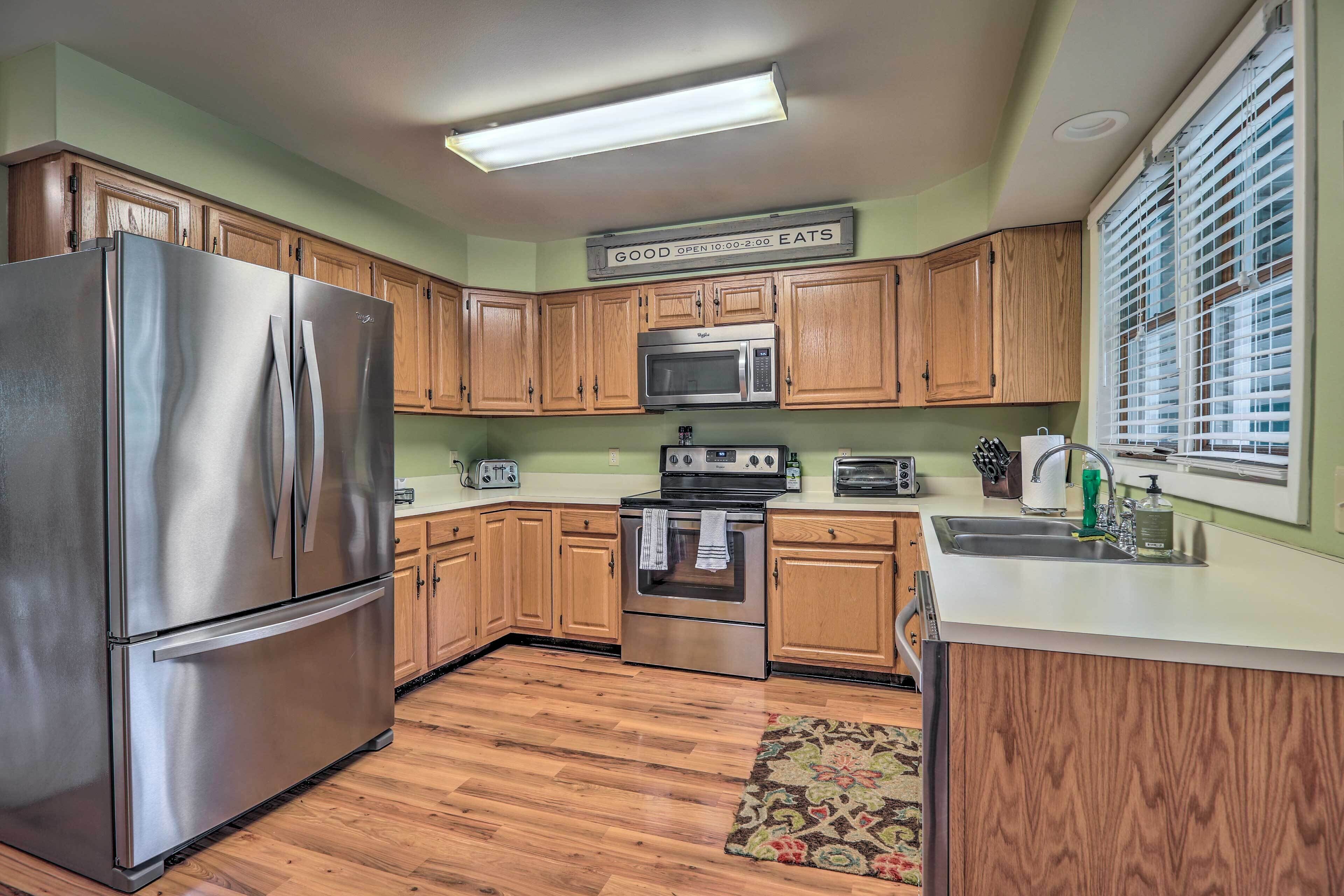 A kitchen with wooden cabinets, a stainless steel refrigerator, a microwave, and a stove.