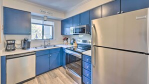 Una cocina moderna con gabinetes azules, un refrigerador de acero inoxidable, un microondas y un horno.