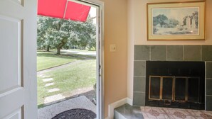 A room with a fireplace, a door leading outside, and a framed picture on the wall. - Baton Rouge Townhome w/ Pool Access - 7 Mi to Lsu! (Baton Rouge)