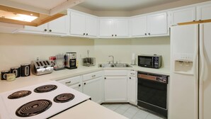 A kitchen with white cabinets, a stove, a microwave, a dishwasher, and a refrigerator. - Baton Rouge Townhome w/ Pool Access - 7 Mi to Lsu! (Baton Rouge)