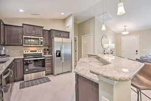 A modern kitchen with stainless steel appliances, granite countertops, and dark wooden cabinets. - Private Heated Pool, Near Warm Mineral Springs (North Port)