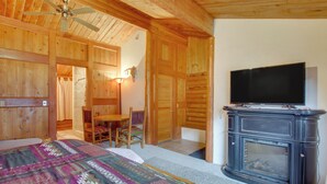 L’intérieur d’un chalet en bois comprend un lit, un téléviseur, une cheminée et un coin repas.