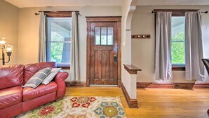 A room with a wooden door, a red leather sofa, and a patterned rug. - Stylish St. Louis Retreat w/ Great Location! (St. Louis)