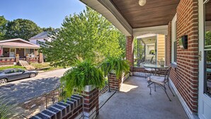 A covered porch with a brick wall, a table and chairs, and a view of the street. - Stylish St. Louis Retreat w/ Great Location! (St. Louis)