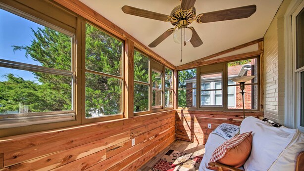 A sunroom with wooden walls, large windows, a ceiling fan, and a cushioned bench with pillows. - Stylish St. Louis Retreat w/ Great Location! (St. Louis)