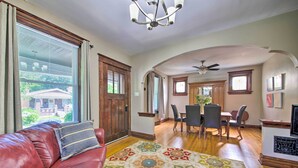 A spacious living room with a red leather couch, a patterned rug, wooden flooring, a dining area with a table and chairs, and a fireplace. - Stylish St. Louis Retreat w/ Great Location! (St. Louis)