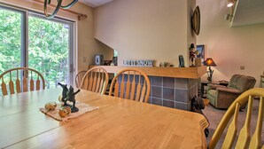 Comedor con una mesa de madera, sillas y vistas a árboles a través de amplios ventanales.