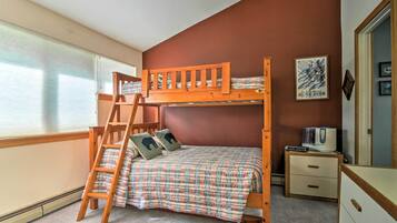 A bunk bed with a ladder, a bedside table, a nightstand, and a poster on the wall.