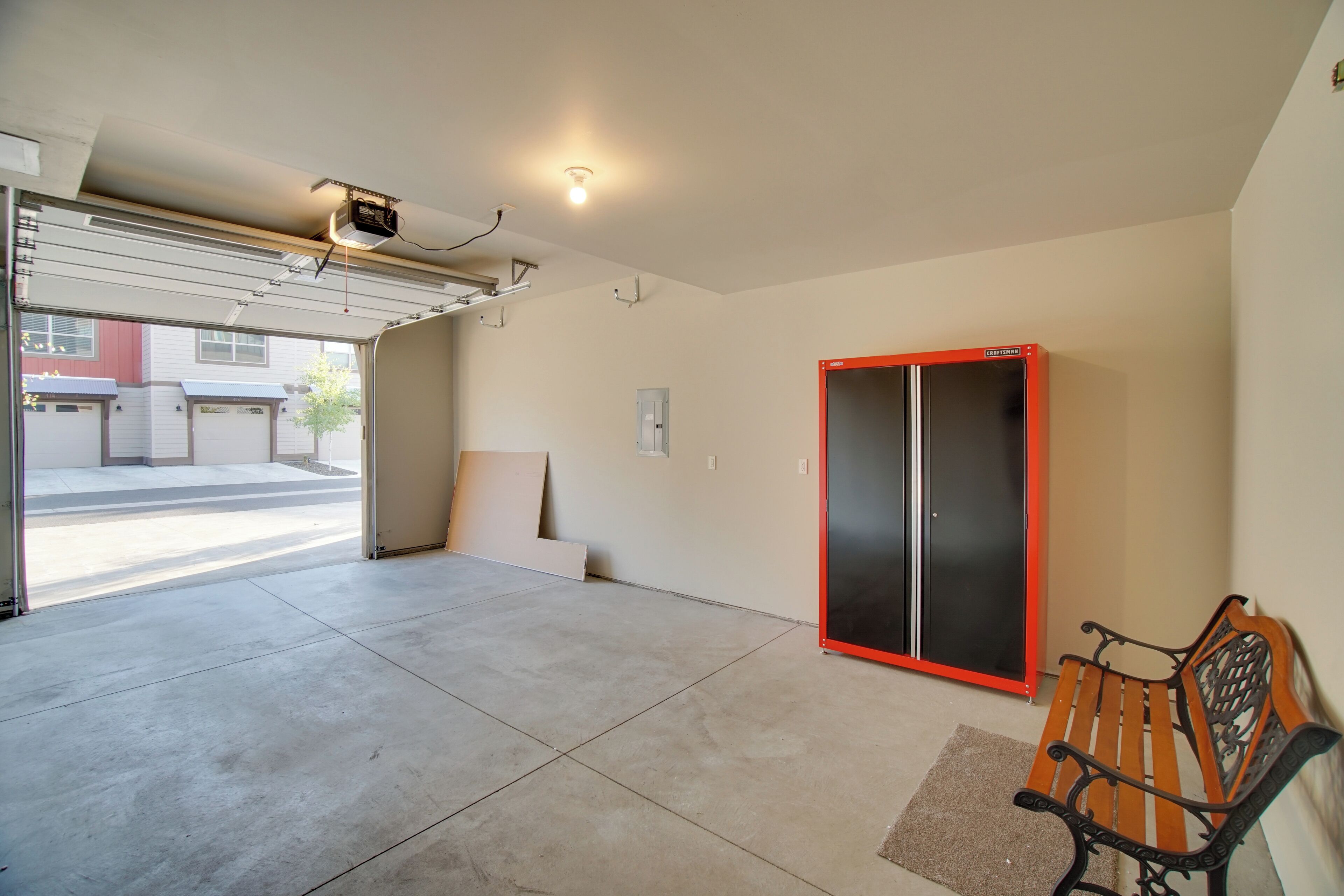 Un garage avec un établi, une armoire à ossature rouge et un sol en béton.