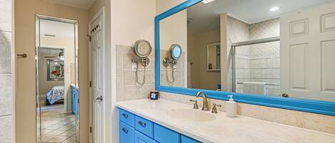 Une salle de bain avec un grand miroir, des meubles bleus et un lavabo.